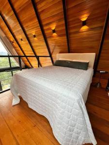 1 dormitorio con cama blanca en el techo de madera en Cabanas 96, en Bento Gonçalves