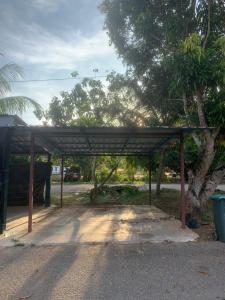 ein überdachter Bereich in einem Park mit einem Baum in der Unterkunft Zulaika Homestay in Kampung Gurun
