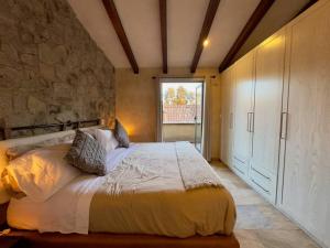 - une chambre avec un grand lit et un mur en pierre dans l'établissement Sol en Val´Quirico, à Santeagueda