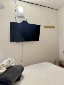 een slaapkamer met een bed en een flatscreen-tv aan de muur bij Luky's Rooms in San Andrés