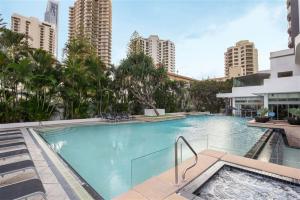 a large swimming pool with palm trees and buildings at Studio with Resort Facilities in Prime Location in Gold Coast