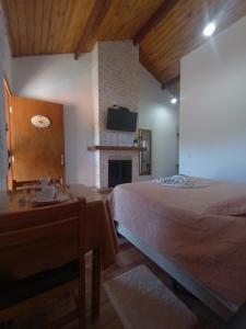 a bedroom with a bed and a table and a fireplace at Recanto lavinia in Monte Verde