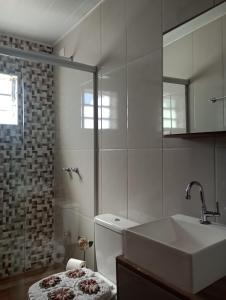 ein Badezimmer mit einem Waschbecken, einem WC und einem Spiegel in der Unterkunft Recanto lavinia in Monte Verde