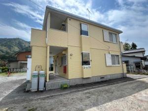 a yellow house with two parking meters in front of it at コーポアス in Nikko