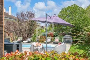 a purple umbrella and chairs next to a pool at La Maison des Rêves - Avec parking et Piscine in Soisy-sous-Montmorency