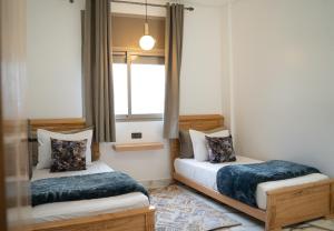 two beds in a room with a window at La Terrassa appartement climatisé in Azrou