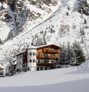 a building in the snow in front of a mountain at Almhof-Reithof Pitztal in Sankt Leonhard im Pitztal