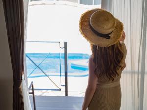 a woman wearing a straw hat looking out a window at Villa Vorla in Miyako Island
