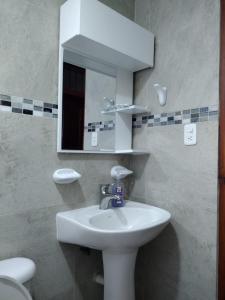 a bathroom with a sink and a mirror and a toilet at Hermoso Departamento in Loja