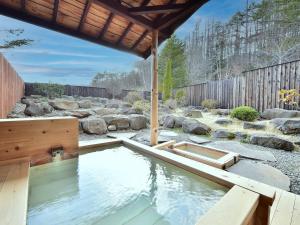 una piscina de agua en un patio con rocas en 乗鞍高原温泉 アルプホルン en Matsumoto