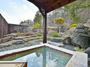 einen Pool inmitten eines Gartens in der Unterkunft 乗鞍高原温泉 アルプホルン in Matsumoto