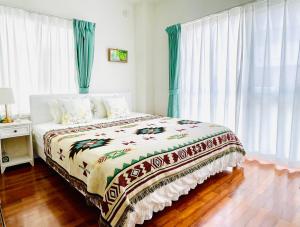 sypialnia z łóżkiem i oknem z zasłonami w obiekcie Sunset Beach House w mieście Chatan