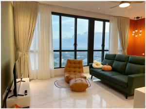 een woonkamer met een groene bank en grote ramen bij Red Sunset Studio Sky 88 JB Town in Johor Bahru