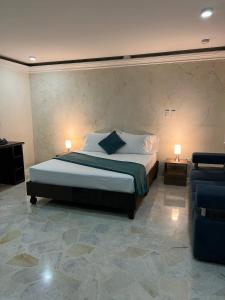 ein Schlafzimmer mit einem Bett mit zwei Lampen und einem Sofa in der Unterkunft Hotel Ingenio NJ in Cali