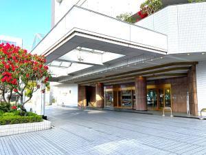 a large white building with red flowers in front of it at Hotel Springs Makuhari in Chiba