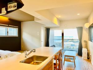 cocina con fregadero y dormitorio con cama en Stay`sOTARU en Otaru