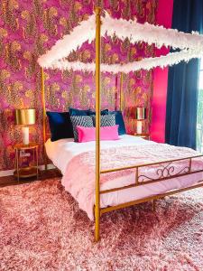 1 dormitorio con cama con dosel y paredes rosas en Dolly's Yacht Club - Cozy Retreat Near Broadway, en Nashville