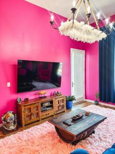 sala de estar con pared de color rosa y TV en Dolly's Yacht Club - Cozy Retreat Near Broadway, en Nashville