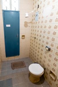 a bathroom with a toilet and a blue door at Quarto 05 Pousada Roosevelt in Uberlândia