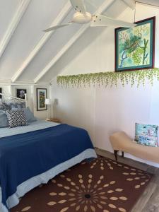 um quarto com uma cama azul e uma cadeira em Bungalow Ocean View wifi em Patillas