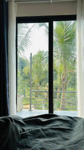- une fenêtre donnant sur un palmier dans l'établissement Đông Sơn Mountain Villa, à Bắc Ninh