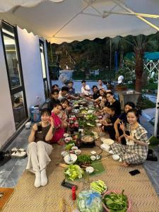 Un groupe de personnes assises autour d'une longue table de nourriture dans l'établissement Đông Sơn Mountain Villa, à Bắc Ninh
