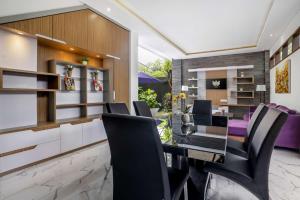a dining room with a glass table and black chairs at Villa Sun Lila by JB Villas in Seminyak