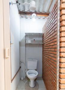a bathroom with a toilet and a brick wall at Quarto 03 Pousada Roosevelt in Uberlândia