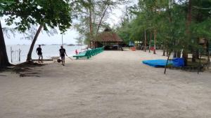 twee mensen lopen op een strand met een speeltuin bij Madu Tiga Beach and Resort in Tanjung Pinang 