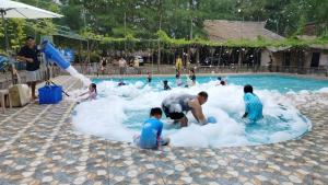 a group of people playing in a pool with foam at Madu Tiga Beach and Resort in Tanjung Pinang