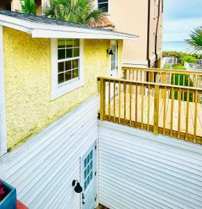 a white house with a balcony with a blue door at Beachside Historic Cottage - Steps to Sand! in Clearwater Beach