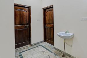 a bathroom with a sink and two wooden doors at Super OYO Pg On Ganges in Rāmnagar