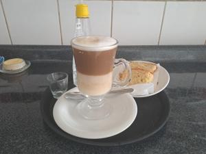 una taza de café sentada en un plato con pan en HOSTAL EL AROMO.., en Chillán