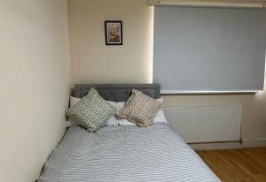 uma cama com almofadas num quarto em Wembley Stadium Serviced Apartment 2, 12mins to Central London em Londres