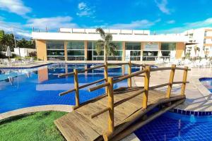 Flat completo em Muro Alto - Porto de Galinhas في إيبوجوكا: حمام سباحة مع مقاعد خشبية أمام المبنى