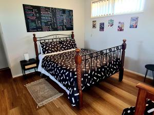 una camera da letto con un letto con una tavola appesa al muro di The Corner Store B&B entire property a Stawell