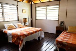 - une chambre avec un lit et 2 fenêtres dans l'établissement Maison d’hôtes bord de mer ia orana lodge, à Moorea