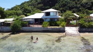 2 personnes dans l'eau devant une maison dans l'établissement Maison d’hôtes bord de mer ia orana lodge, à Moorea