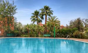 a large swimming pool with palm trees in the background at La Perle de l'Atlas by Golf Resort in Marrakech