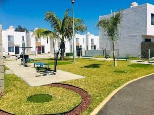 a park with benches and palm trees in front of a building at Casa santeli miramar in Ciudad Madero