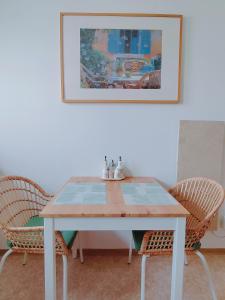 Große Ferienwohnung Burgenland في آيزنشتات: طاولة غرفة طعام مع كرسيين وصورة على الحائط