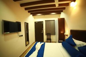 a bedroom with a bed and a flat screen tv at SAPPHIRE INN in Puducherry