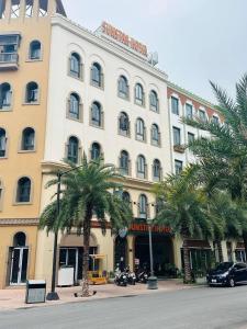 un grand bâtiment blanc avec des palmiers devant lui dans l'établissement Sunstar Hotel, à Hạ Long