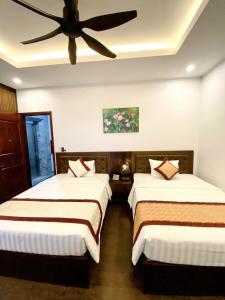 two beds in a room with a ceiling fan at Sunstar Hotel in Ha Long