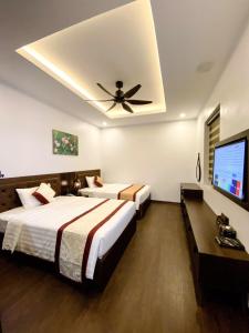 2 bedden in een hotelkamer met een plafondventilator bij Sunstar Hotel in Ha Long