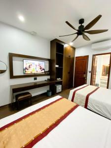 a bedroom with two beds and a flat screen tv at Sunstar Hotel in Ha Long