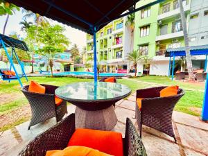 GoaにあるHotel The Golden Shivam Resort - Big Swimming Pool Resort In Goaのパティオ(ガラスのテーブル、椅子、ブランコ付)