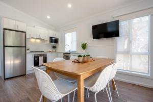 ナンブッカ・ヘッズにあるBIG4 Tasman Holiday Parks - Nambucca Headsのキッチン(木製テーブル、白い椅子付)