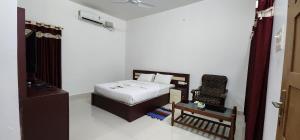 a small bedroom with a bed and a chair at Pepper and Clove Enclave in Puliyara