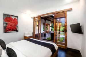 een slaapkamer met een bed en een flatscreen-tv bij Villa Jepun by BaliSuperHost in Ubud